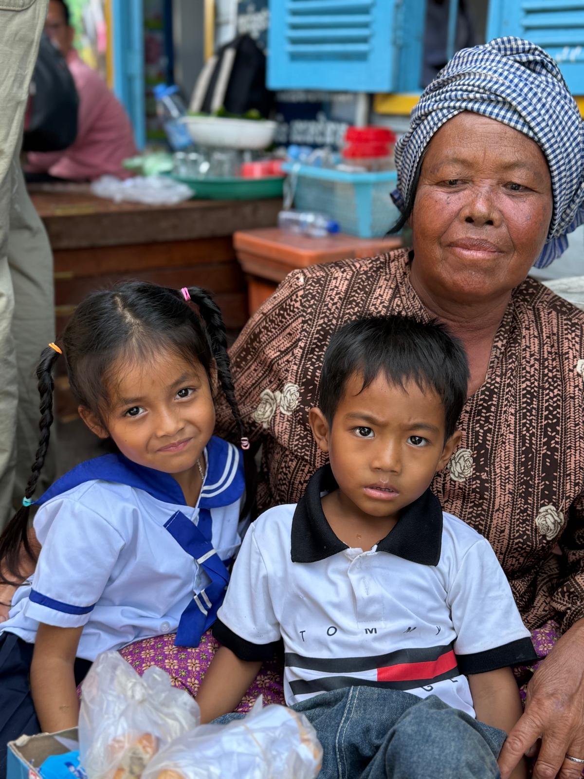 A grandmother sitting with two children in school uniforms