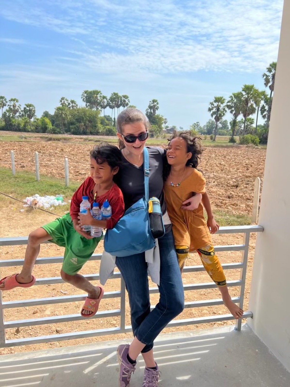 A team member laughing with two children on a balcony overlooking the fields