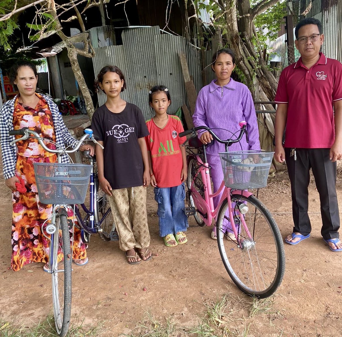 A mother and her children receiving bicycles, standing together outside their home
