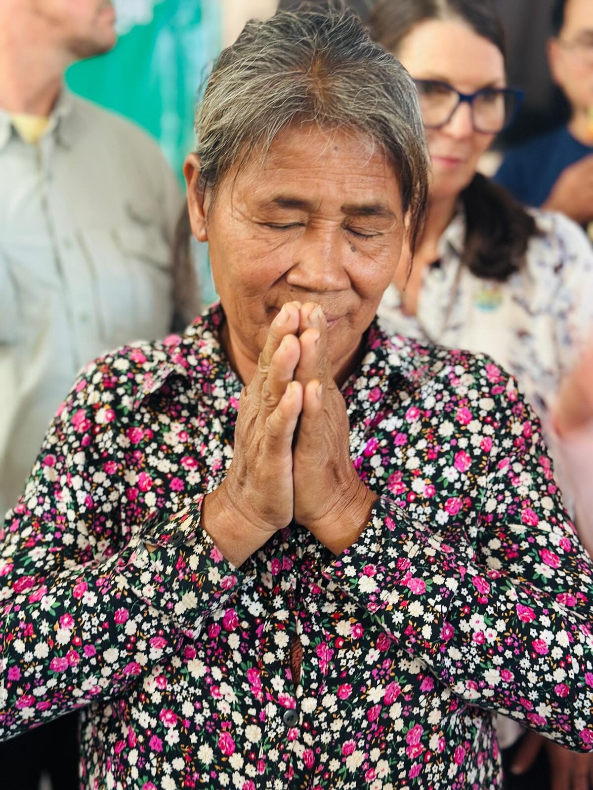 Members of the Pursat community praying together with hands raised