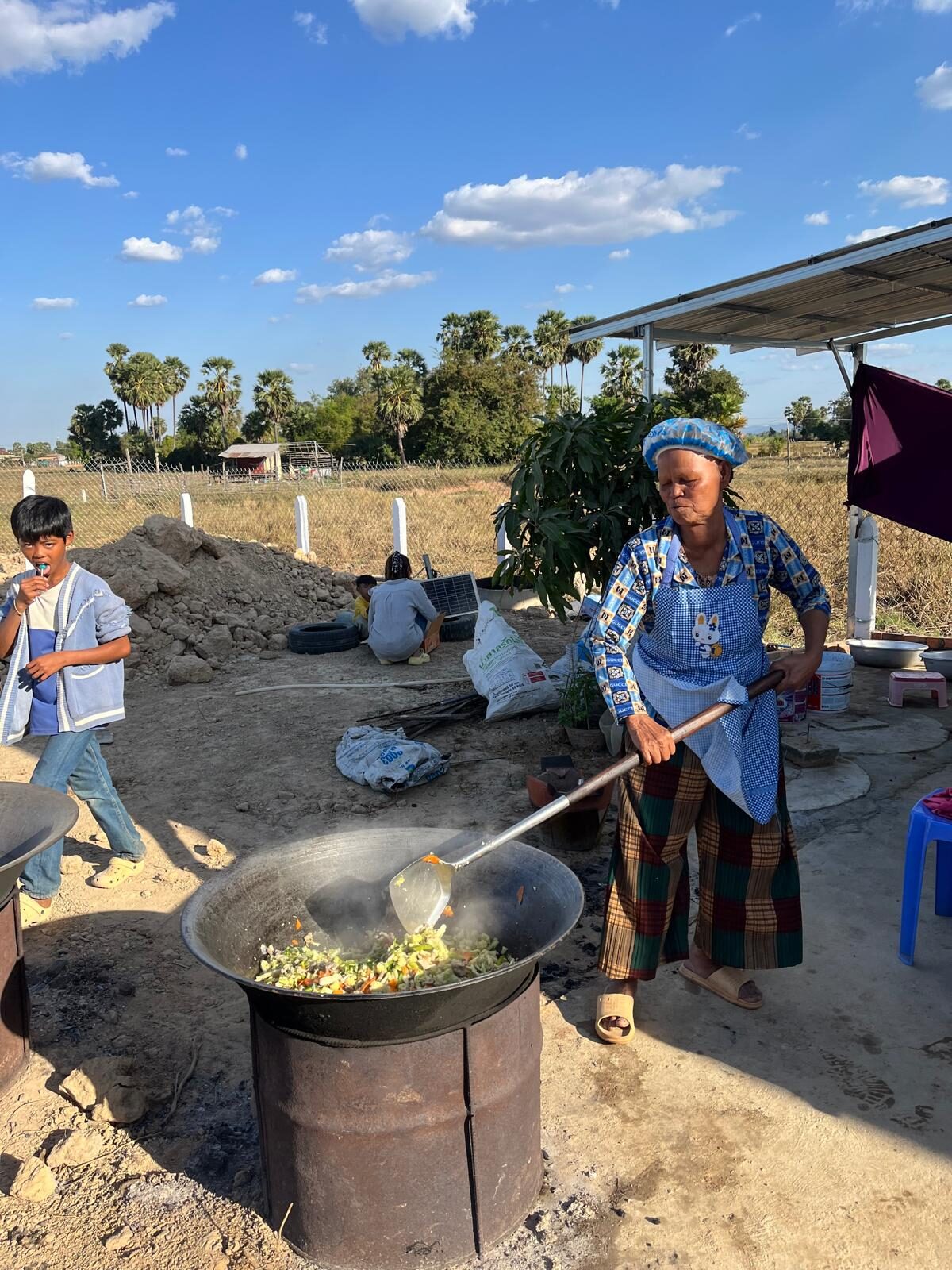 Women cooking together over large pots to prepare a community meal in Pursat