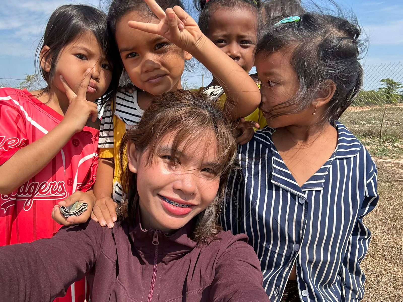 A Light of Cambodia teacher sitting with a group of children during a lesson in Pursat